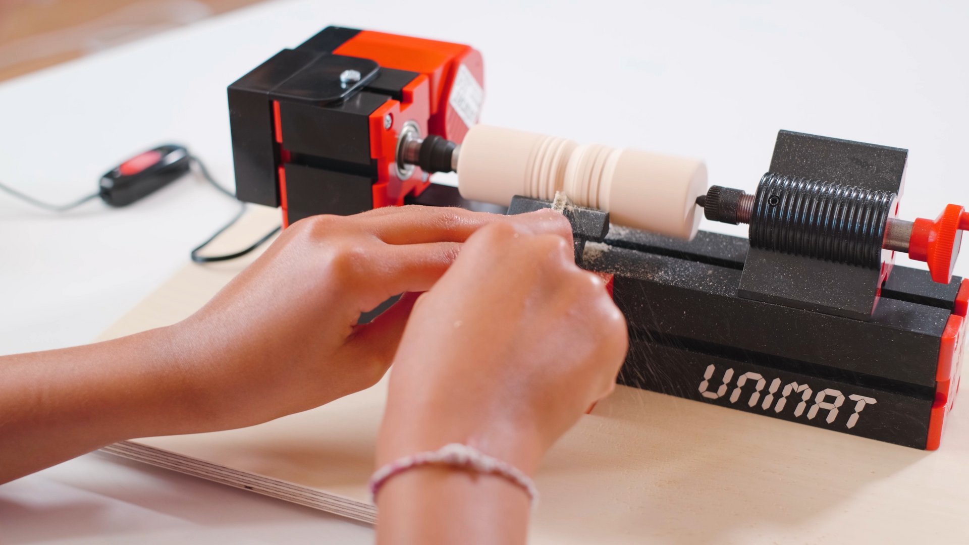 Girl is working on a wooden model with the UNIMAT 1 wood lathe